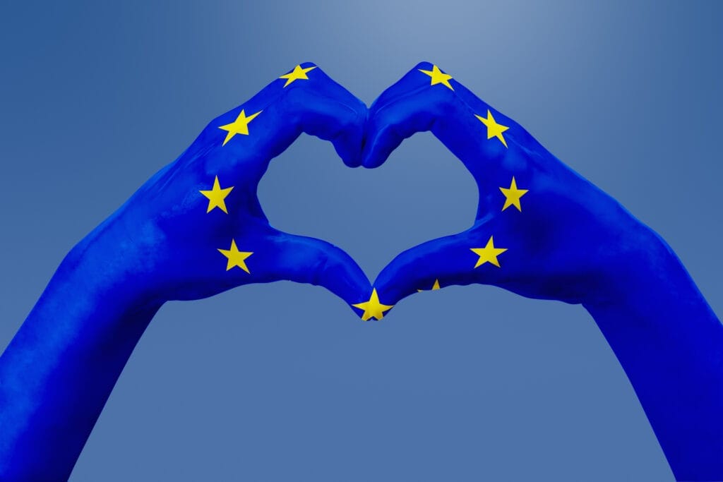 Hands flag of European Union, shape a heart. Concept of country symbol, on blue sky.
